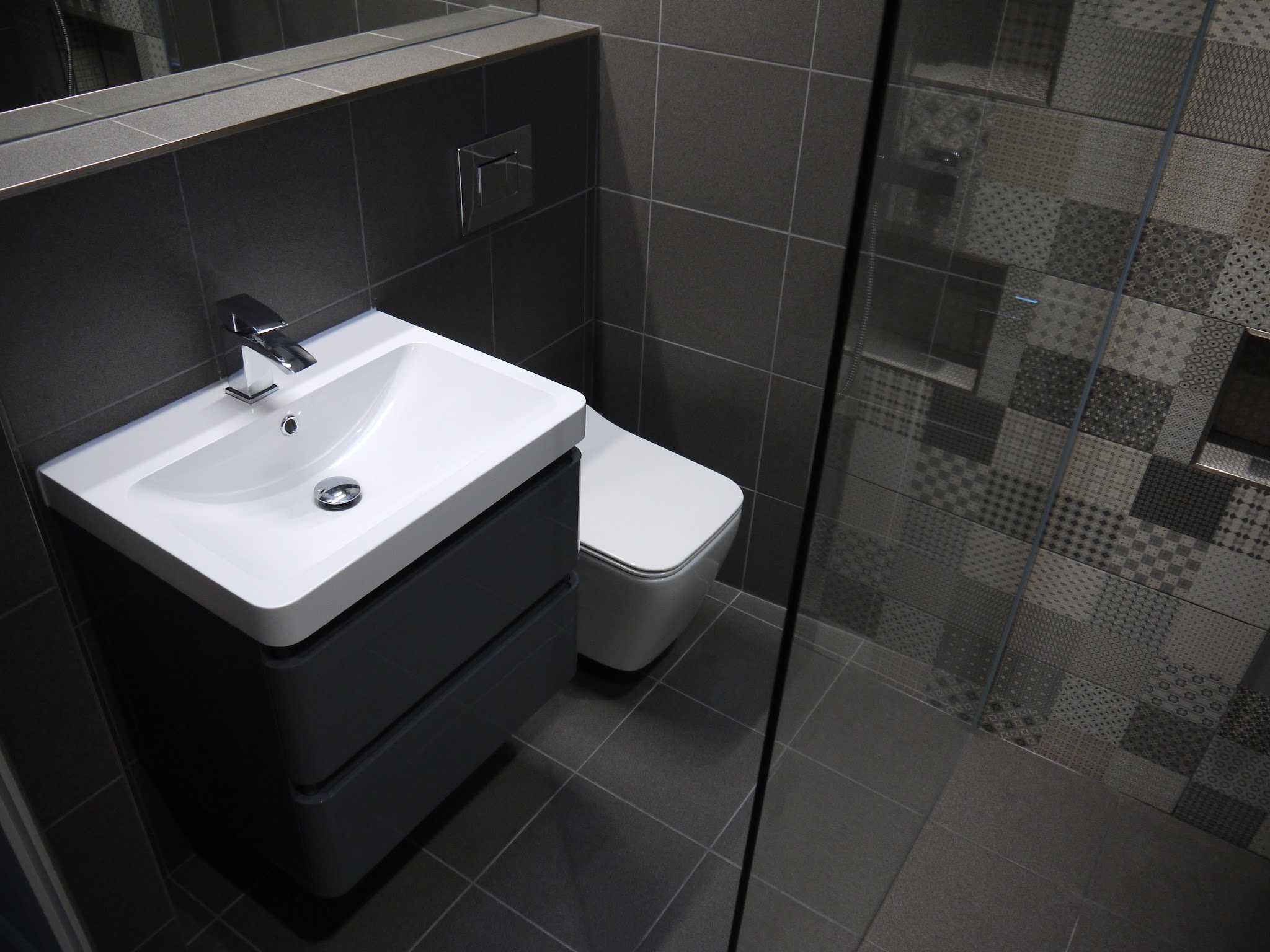Charcoal floor and wall tiles with a patterned shower.